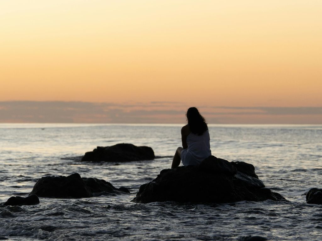 Femme assise face à la mer dans un moment de calme et d’introspection